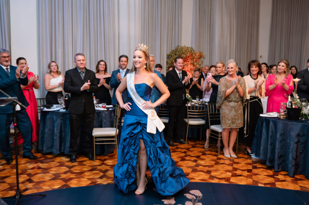 O Clube do Comércio de Erechim celebrou, na noite de 11 de abril, seus 91 anos de história com um elegante jantar-baile que teve como ponto alto a coroação da nova Rainha, Eduarda Oro Remor. O evento reuniu associados, convidados, autoridades e representantes da comunidade em uma programação que evidenciou a importância do clube na vida social, cultural e afetiva do município. A recepção foi conduzida pelo casal presidente, Magda Vendruscolo Zago e Luís Carlos Zago, juntamente com o casal diretor social, Manuela e Diego D’Agostini, que acolheram os convidados ao lado da então Rainha, Isadora Rigo Mocelin, dando início à solenidade que marcou a celebração do aniversário e a transição de reinado.